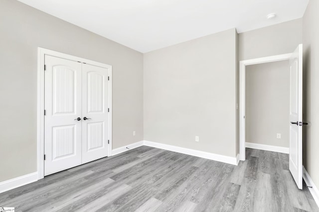 unfurnished bedroom with a closet, baseboards, and wood finished floors