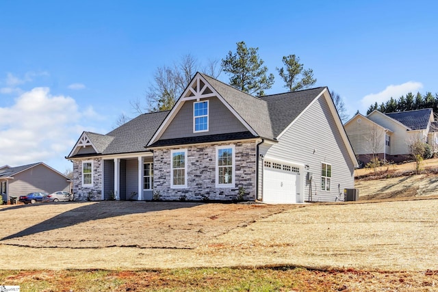 view of front of house featuring an attached garage, stone siding, dirt driveway, and central AC