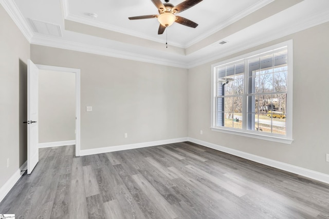 unfurnished room with wood finished floors, a raised ceiling, visible vents, and baseboards