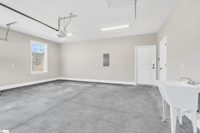 garage with a garage door opener, electric panel, a sink, and baseboards