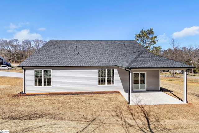 back of property with a patio, a shingled roof, and a lawn