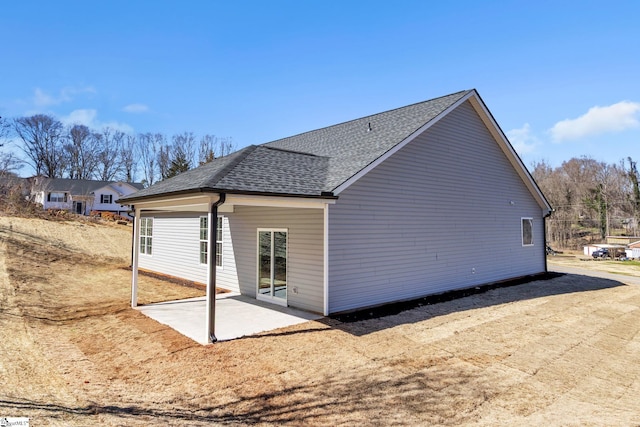 back of house featuring a shingled roof and a patio area