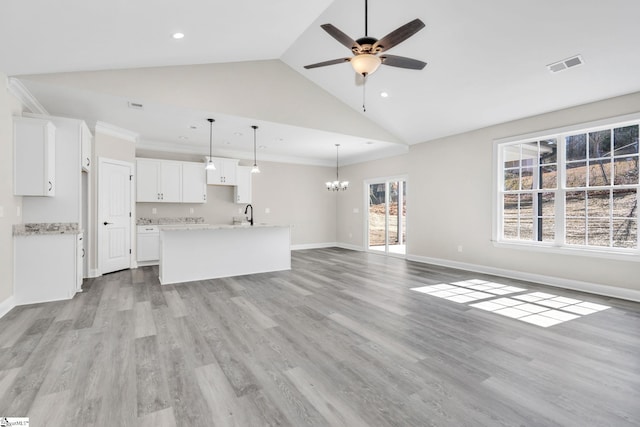 unfurnished living room with ceiling fan with notable chandelier, crown molding, visible vents, and light wood-style floors