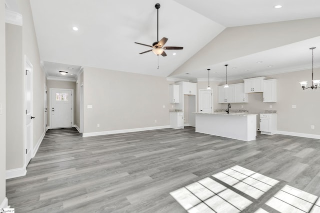 unfurnished living room with baseboards, ornamental molding, light wood-type flooring, high vaulted ceiling, and ceiling fan with notable chandelier