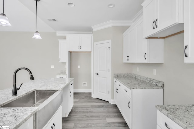 kitchen featuring light stone counters, a sink, visible vents, white cabinetry, and light wood-type flooring