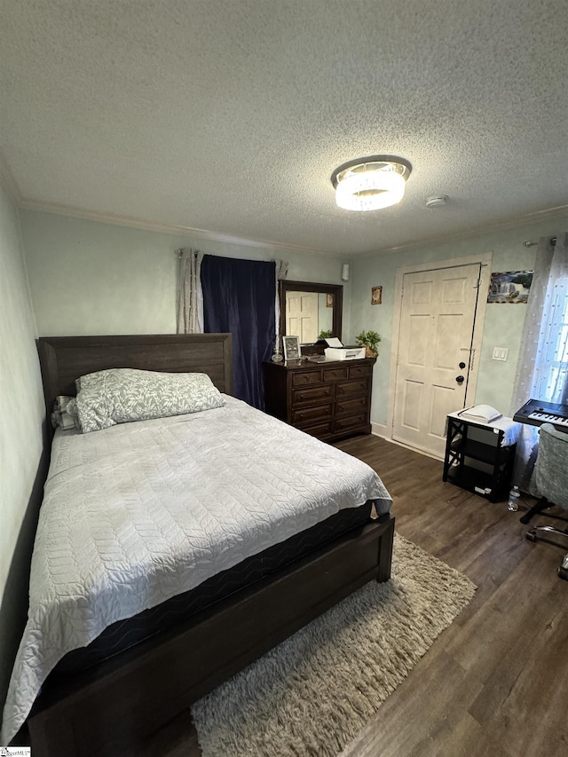 bedroom with a textured ceiling, dark wood-type flooring, and ornamental molding