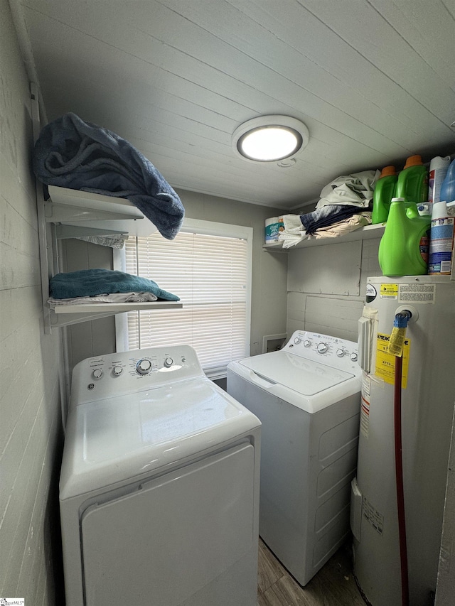 laundry area featuring concrete block wall, laundry area, washing machine and dryer, and water heater