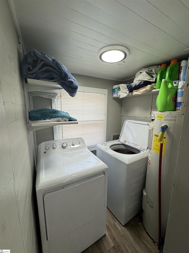 clothes washing area featuring concrete block wall, electric water heater, wood finished floors, washer and dryer, and laundry area