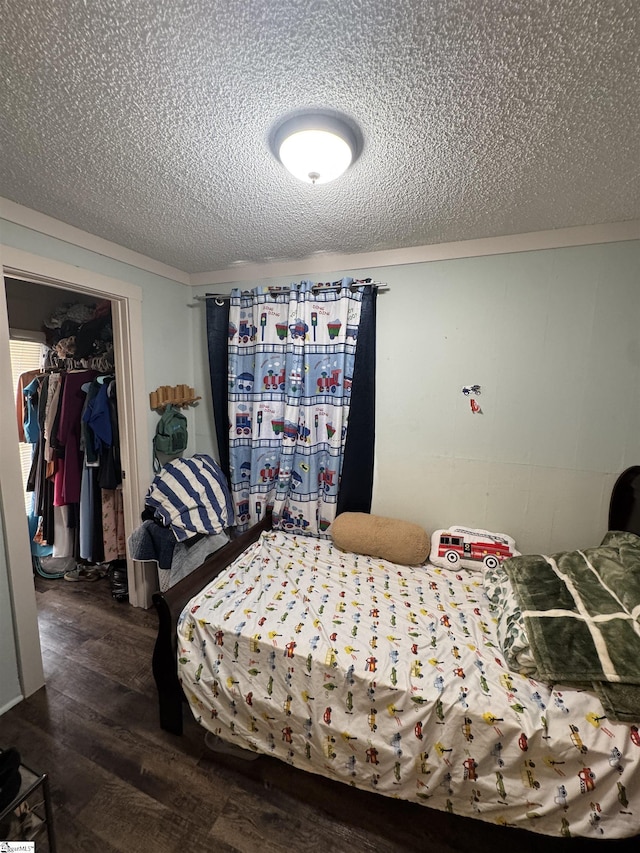 bedroom with a textured ceiling, a walk in closet, and wood finished floors