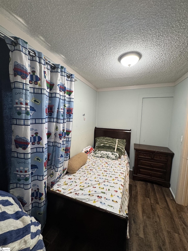 bedroom with a textured ceiling, wood finished floors, and crown molding