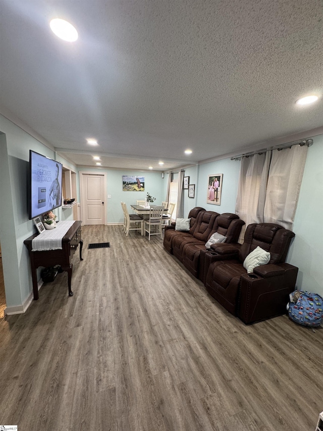 living area with a textured ceiling, baseboards, wood finished floors, and recessed lighting