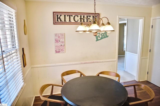 dining room with a wainscoted wall, a chandelier, crown molding, and wood finished floors