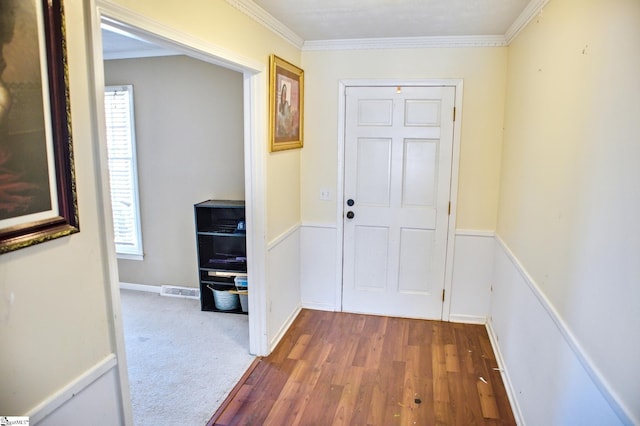 hallway featuring visible vents, crown molding, baseboards, and wood finished floors