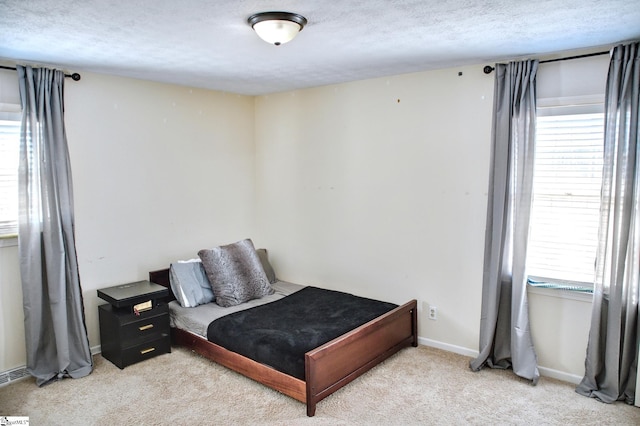 bedroom featuring baseboards, a textured ceiling, and light colored carpet