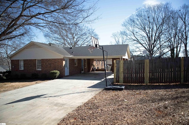 view of side of home with a carport, brick siding, concrete driveway, and fence