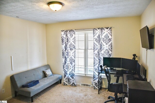 carpeted home office featuring baseboards, visible vents, and a textured ceiling