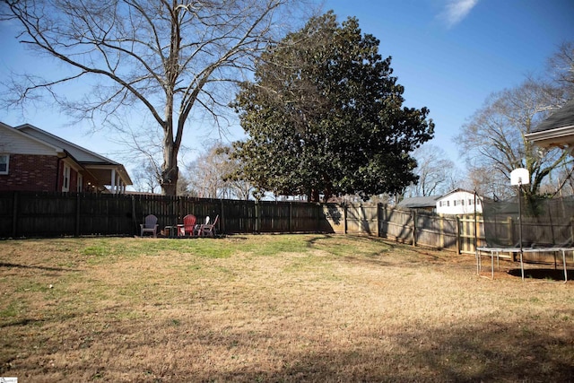 view of yard with a trampoline and a fenced backyard