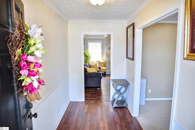 hall featuring dark wood-style floors, baseboards, and ornamental molding