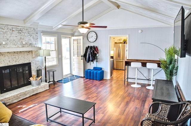 living room with a glass covered fireplace, lofted ceiling with beams, and wood finished floors