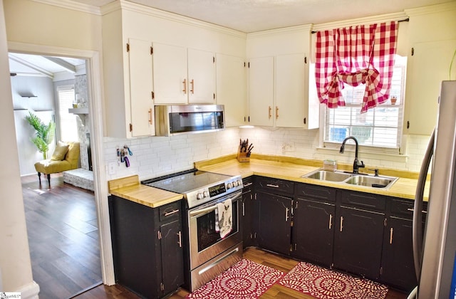 kitchen featuring white cabinets, crown molding, stainless steel appliances, and a sink