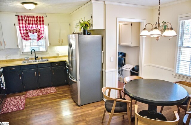 kitchen featuring wood finished floors, freestanding refrigerator, crown molding, a healthy amount of sunlight, and a sink