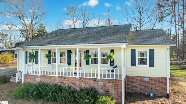 view of front of home with crawl space, covered porch, and roof with shingles