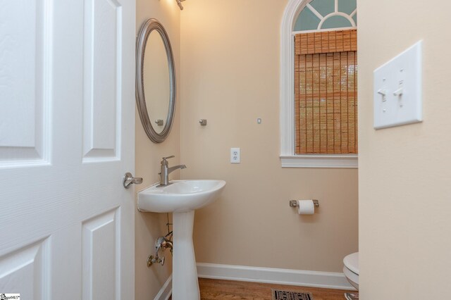 half bath featuring visible vents, a sink, toilet, and baseboards