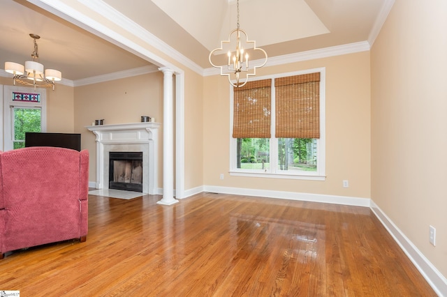 unfurnished living room with a fireplace with flush hearth, ornamental molding, wood finished floors, a chandelier, and baseboards