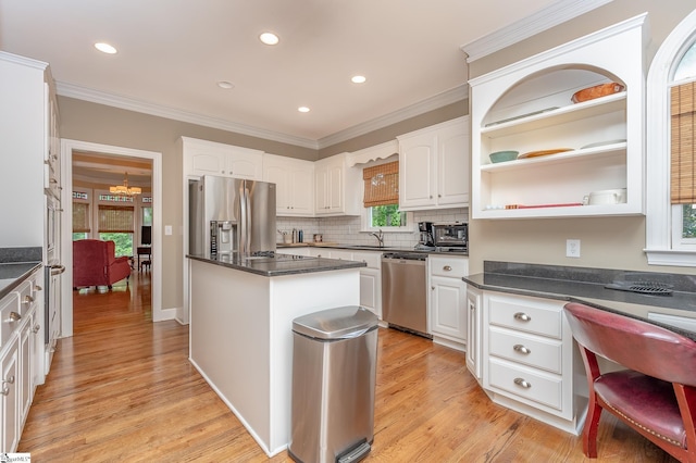 kitchen with light wood-style flooring, appliances with stainless steel finishes, built in desk, and ornamental molding