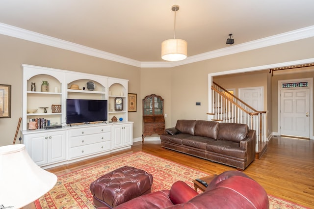 living area featuring stairs, crown molding, baseboards, and wood finished floors