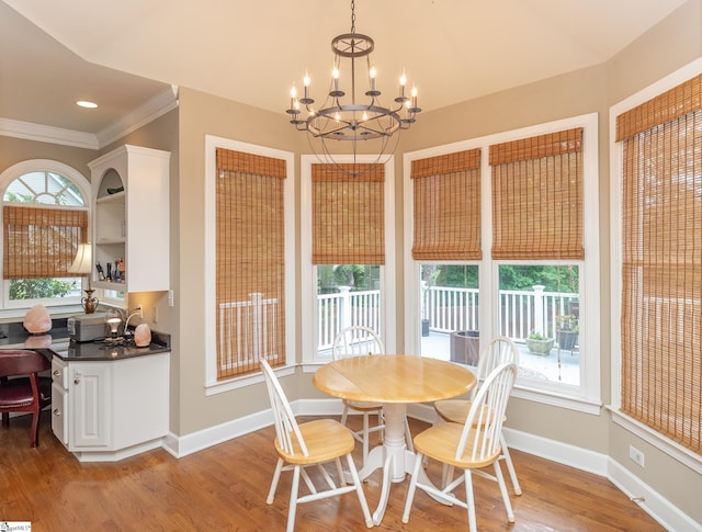 dining area featuring a notable chandelier, ornamental molding, wood finished floors, and baseboards