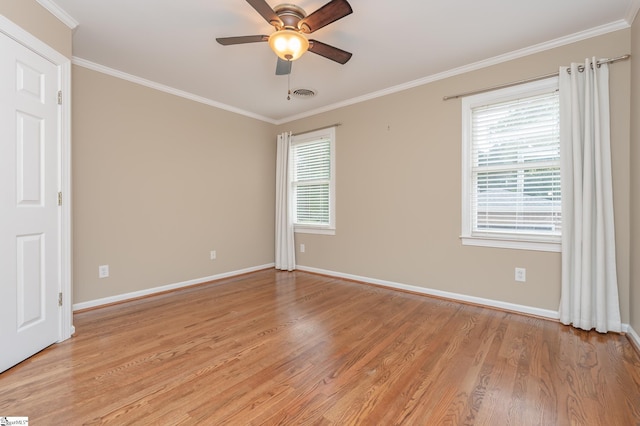 spare room with light wood-type flooring, ornamental molding, and plenty of natural light