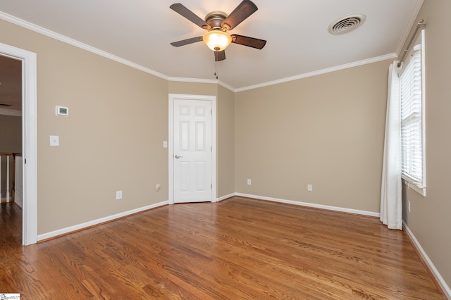 unfurnished room featuring visible vents, wood finished floors, and ornamental molding