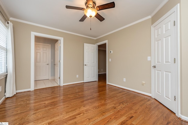 unfurnished bedroom featuring ensuite bathroom, ornamental molding, ceiling fan, light wood-type flooring, and baseboards