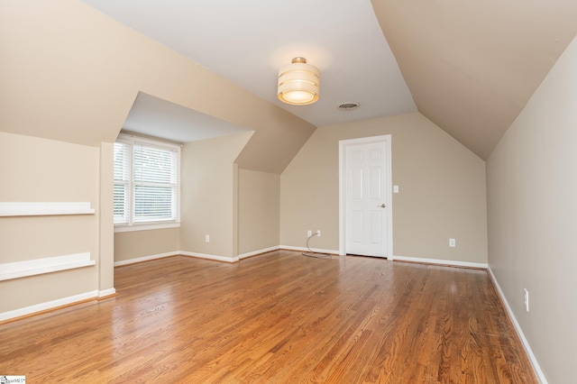 bonus room with visible vents, vaulted ceiling, baseboards, and wood finished floors