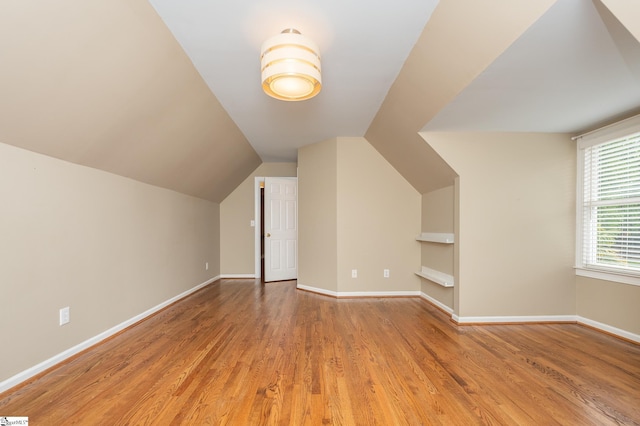 additional living space featuring baseboards, vaulted ceiling, and wood finished floors