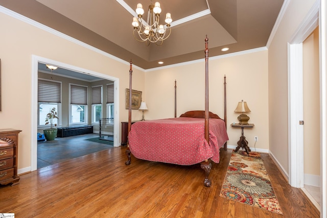 bedroom with ornamental molding, wood finished floors, a raised ceiling, and baseboards