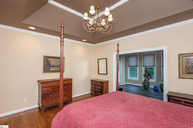 bedroom with baseboards, ornamental molding, wood finished floors, a tray ceiling, and a chandelier