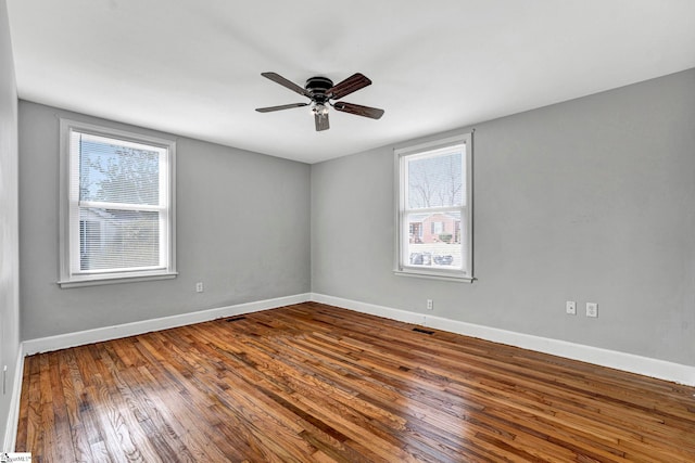 unfurnished room featuring wood-type flooring, a ceiling fan, and baseboards