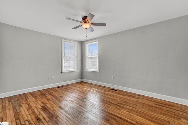 spare room with a ceiling fan, hardwood / wood-style flooring, and baseboards