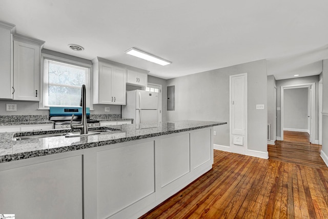 kitchen featuring visible vents, dark wood finished floors, light stone counters, and freestanding refrigerator