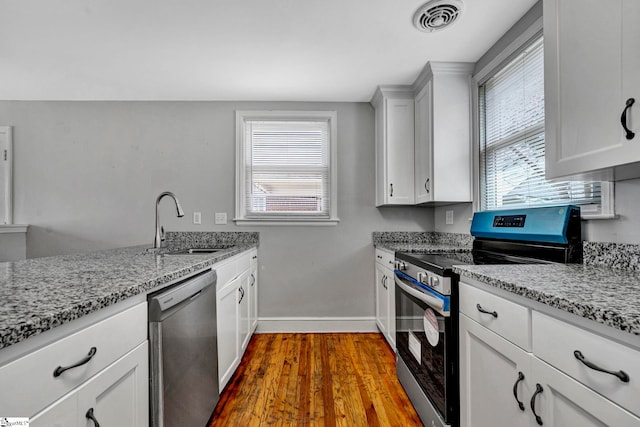 kitchen featuring light stone counters, visible vents, appliances with stainless steel finishes, a sink, and baseboards