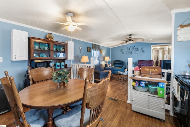 dining room featuring ornamental molding, lofted ceiling, visible vents, and wood finished floors