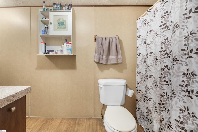 full bath with a shower with shower curtain, toilet, a textured ceiling, vanity, and wood finished floors