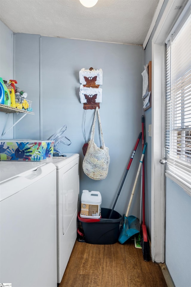 clothes washing area featuring laundry area, a textured ceiling, washer and dryer, and wood finished floors