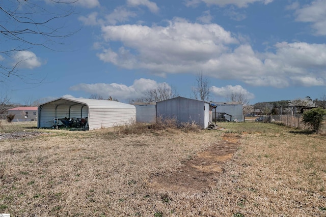 view of outdoor structure with a detached carport, fence, and an outbuilding