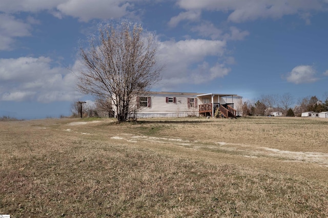 exterior space featuring a rural view, a front lawn, and a wooden deck