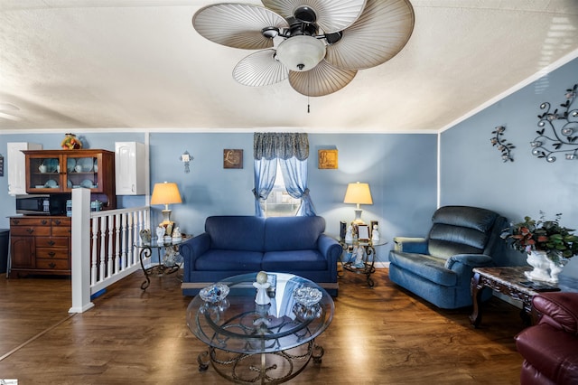 living room featuring ceiling fan, a textured ceiling, ornamental molding, and wood finished floors