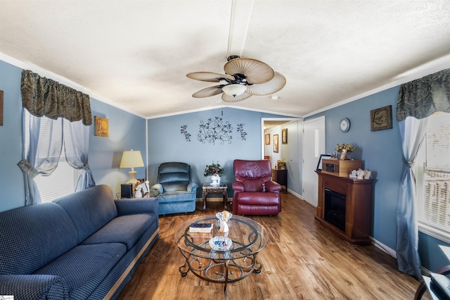 living room with baseboards, lofted ceiling, wood finished floors, crown molding, and a fireplace