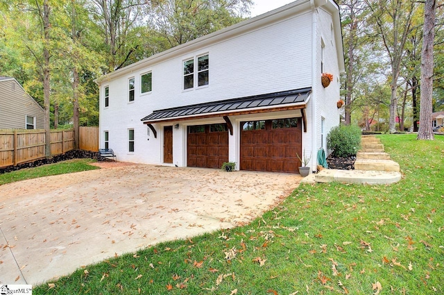 view of front of property featuring a garage, concrete driveway, metal roof, a standing seam roof, and fence